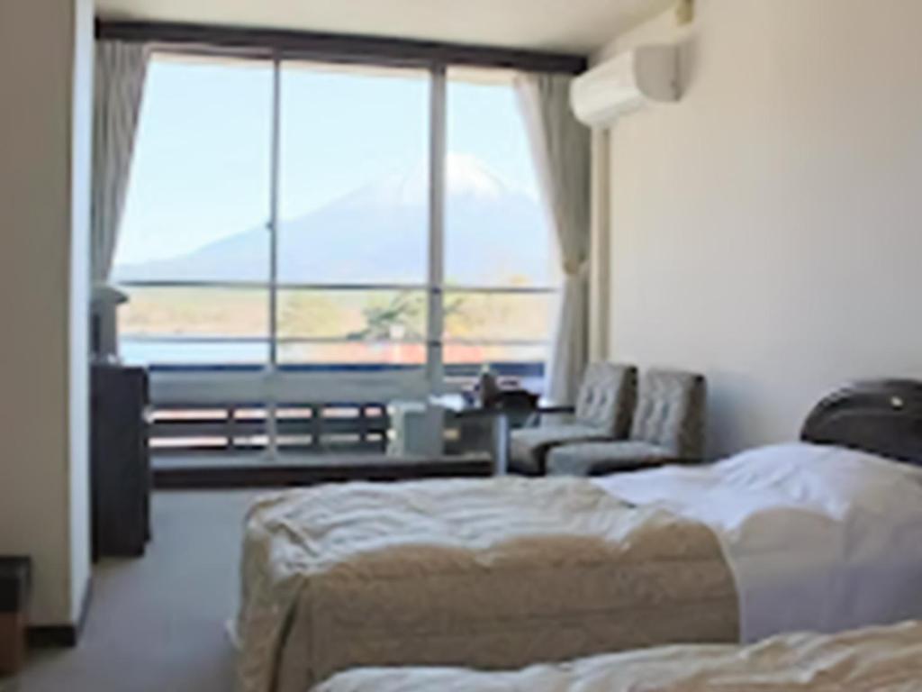 1 dormitorio con 2 camas, sofá y ventana en Shoji Mount Hotel - Vacation STAY 83000v en Narusawa