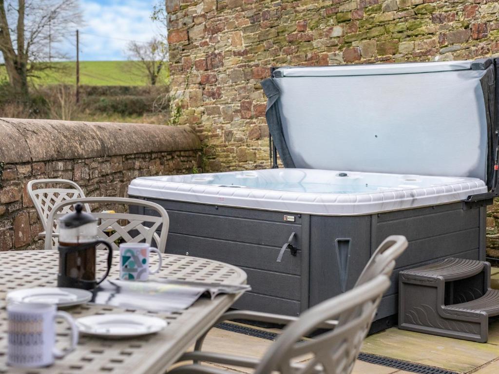 a hot tub on a patio with a table and chairs at 4 Bed in Bideford OAPPL in Monkleigh
