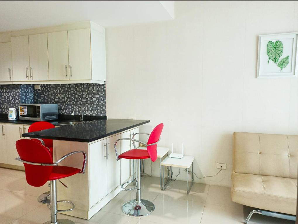 a kitchen with red chairs and a counter top at Minimalist Condotel at SMDC Sea Residences in Manila