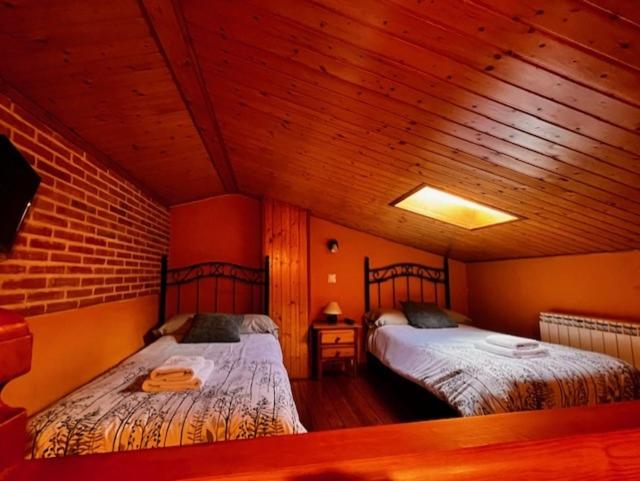 2 camas en una habitación con techos de madera en la cabaña de gredos en San Martín de la Vega del Alberche
