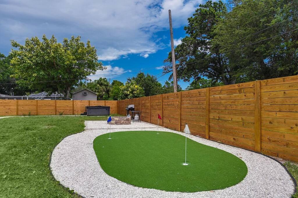 a golf course in a backyard with a wooden fence at Oasis: Hot tub, fire pit, fun! in Vero Beach