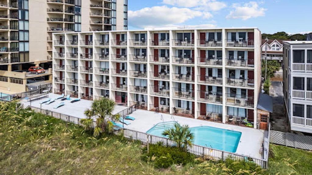an apartment building with a swimming pool and palm trees at The Red Tree Inn in Myrtle Beach