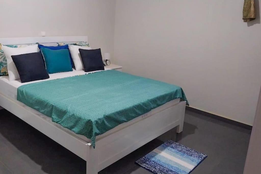 uma cama branca com almofadas azuis num quarto em Cozy Home with Stunning Views! em Ponta do Sol