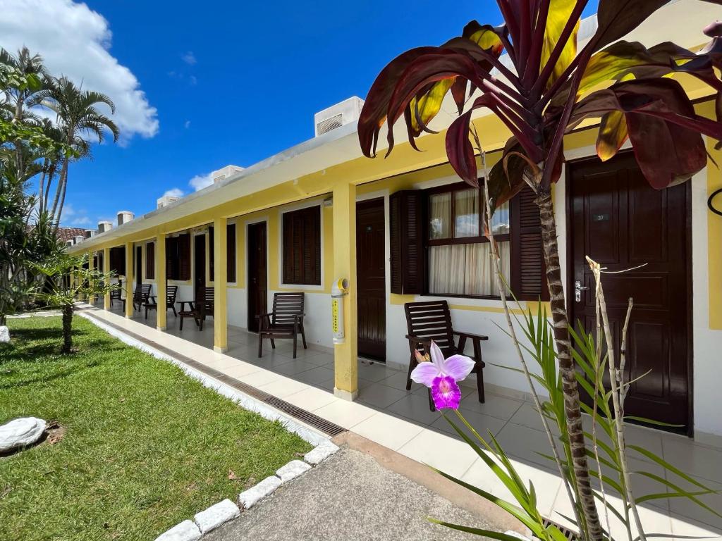 a yellow and white building with chairs and a plant at Hotel Roma in São Sebastião