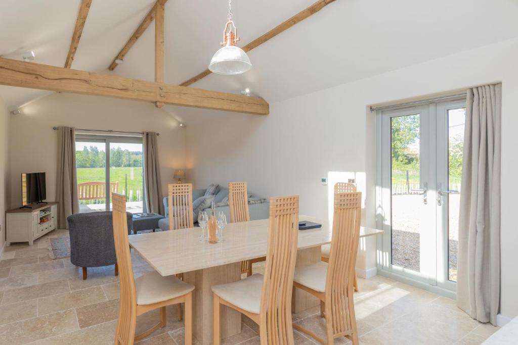 a dining room and living room with a table and chairs at Snipe Meadow Barn in Swafield