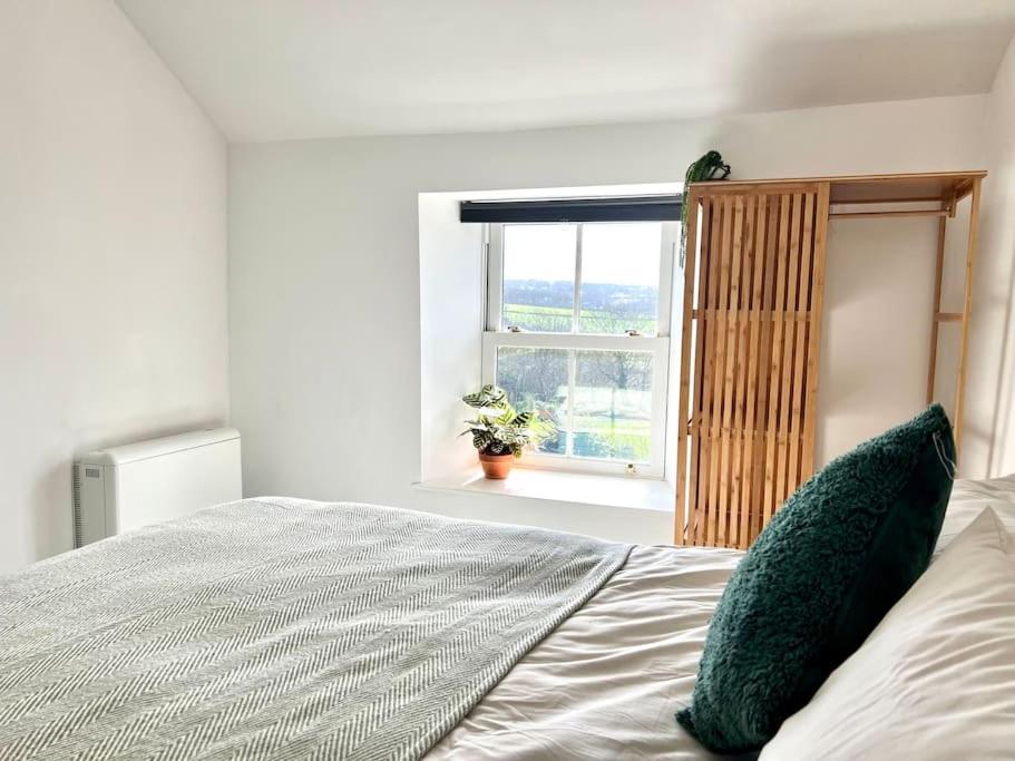 a bed with two pillows in a bedroom with a window at Little Hillside in Porthtowan