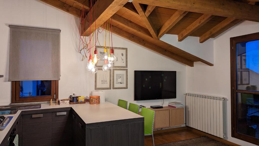 una cucina con tavolo, sedie verdi e TV di B&B Audrey a Varese