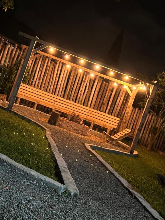 a wooden bench sitting in front of a fence with lights at Recanto Monte Trigo in São Francisco do Sul