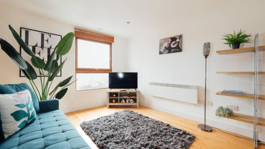 a living room with a blue couch and a tv at Leeds City Centre Dock 2 Bed 2 Bath in Hunslet