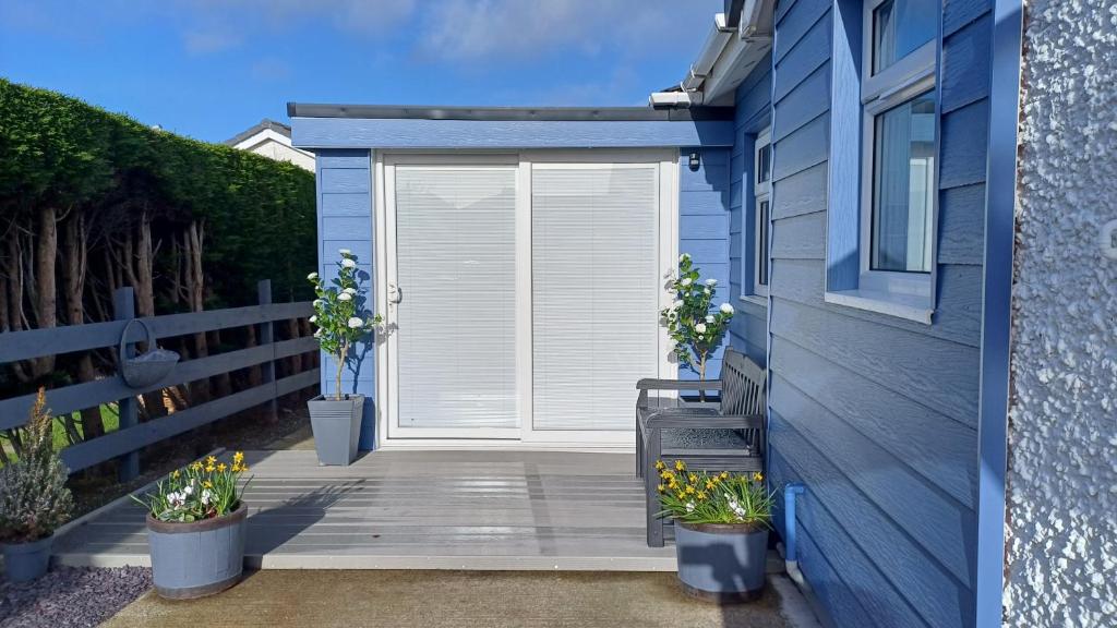 een witte deur op een blauw huis met potplanten bij The Beach House in Valley