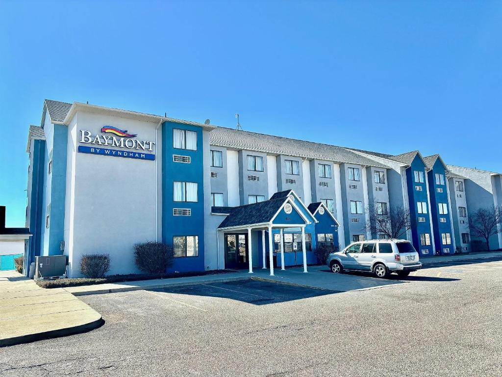 a large building with a car parked in a parking lot at Baymont by Wyndham Farmington in Farmington