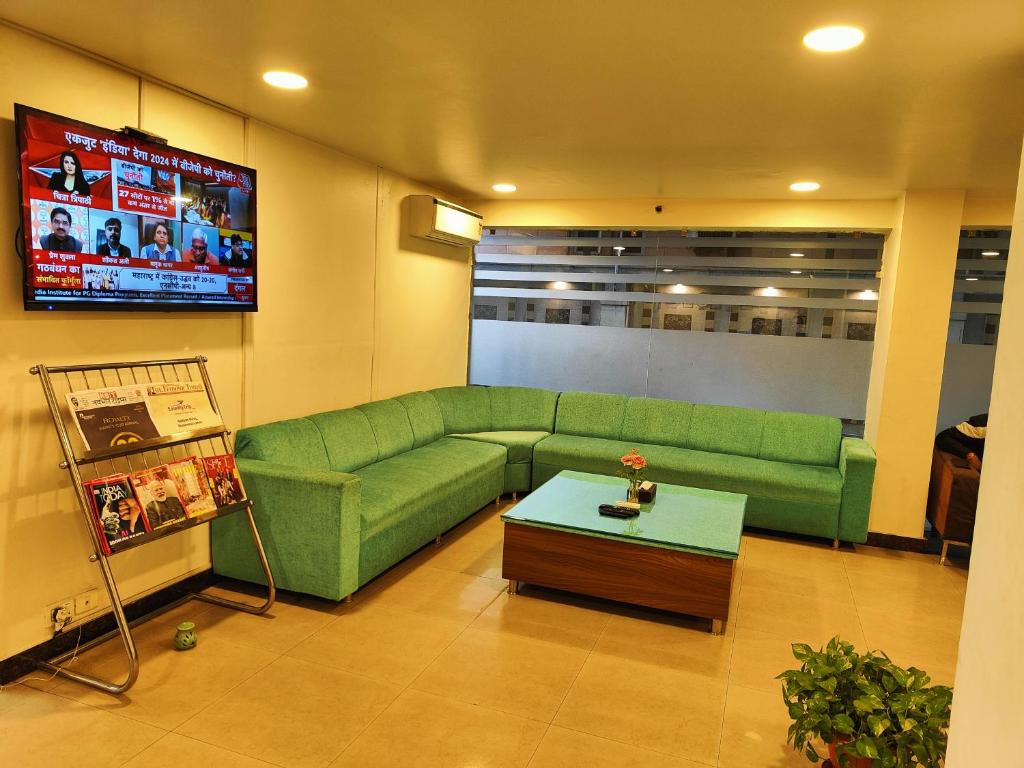 a living room with a green couch and a tv at RoseMallow Tavisha Hotel in New Delhi