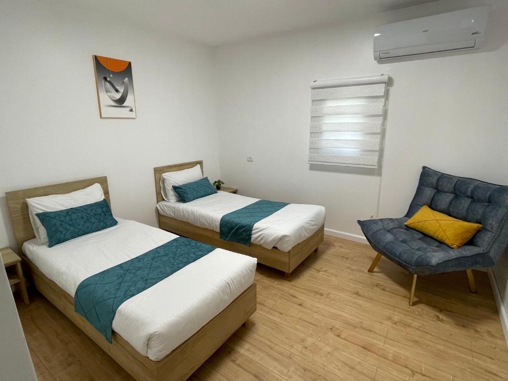 two beds in a room with a chair and a bed sqor at Yellow House Suite in Majdal Shams