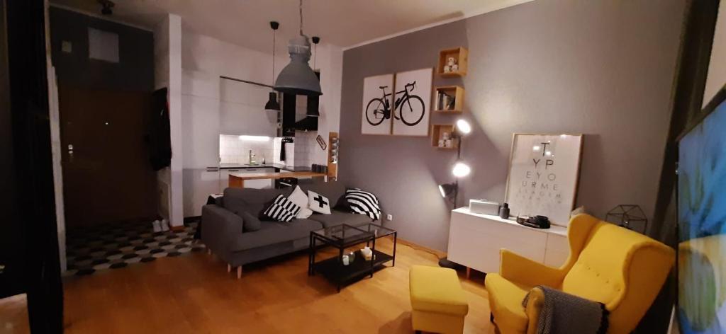 a living room with a gray couch and yellow chairs at Apartament DANI in Nysa
