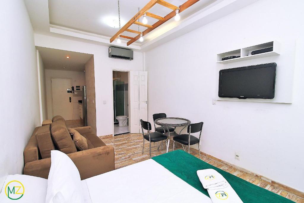 ein Wohnzimmer mit einem Sofa und einem TV an der Wand in der Unterkunft Studio para 4 pessoas com vista mar em Copacabana in Rio de Janeiro