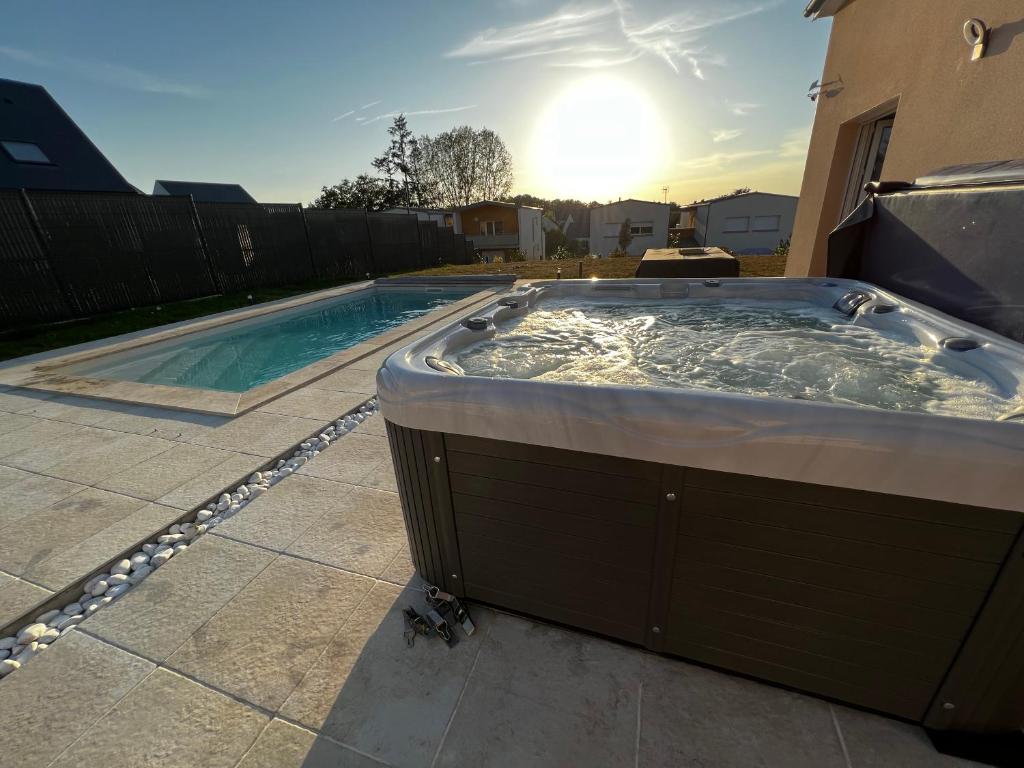 a hot tub in a backyard with the sun in the background at Maison chaleureuse tout confort in Amboise