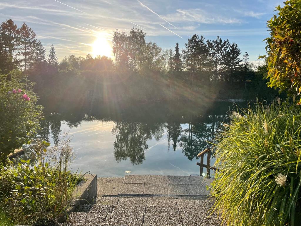 a reflection of the sun in a lake with a dock at Das Haus am See - der idyllische Privatsee nahe Wien in Tulln