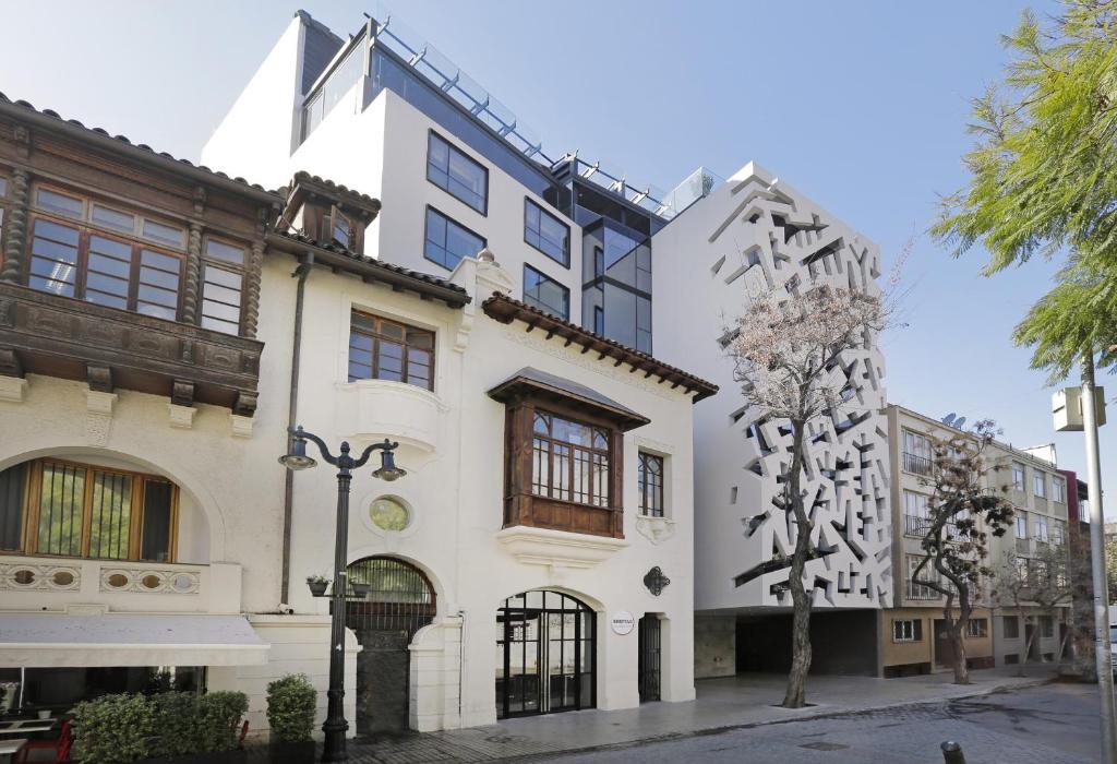 um edifício branco com uma árvore em frente em Hotel Cumbres Lastarria em Santiago