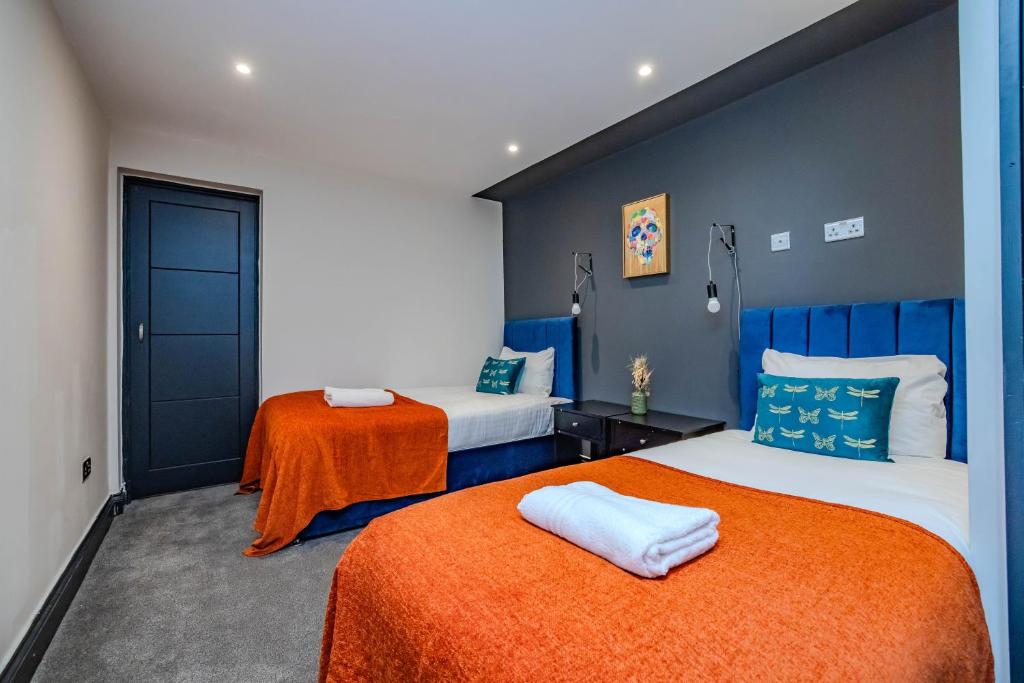 1 Schlafzimmer mit 2 Betten und einer orangefarbenen Decke in der Unterkunft 3 Bedroom 2 Bathroom I Super Central Location I Sleep 9 Guests in Brighton & Hove