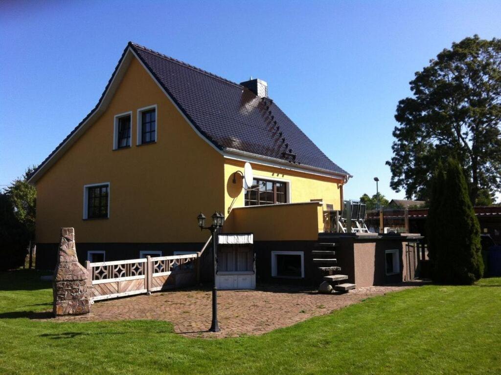 a large yellow house with a fence and a yard at Holiday home Baltic Sea Dream in Zudar