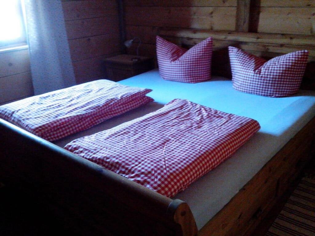 Una cama con almohadas rojas y blancas. en Schauberger Hut mountain hut, en Waldkirchen