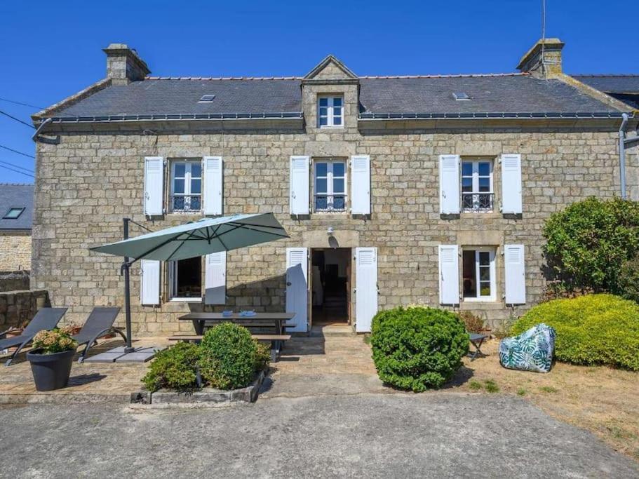 une maison en briques avec un parasol devant elle dans l'établissement Gîte Ty Maen à Plouhinec 56 7pers, à Plouhinec