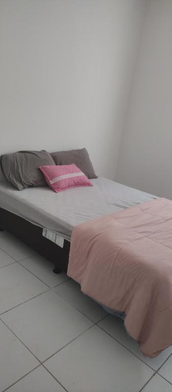 Una cama con almohadas rosas encima. en Linda suite privativa no francês demais cômodos compartilhados, en Marechal Deodoro