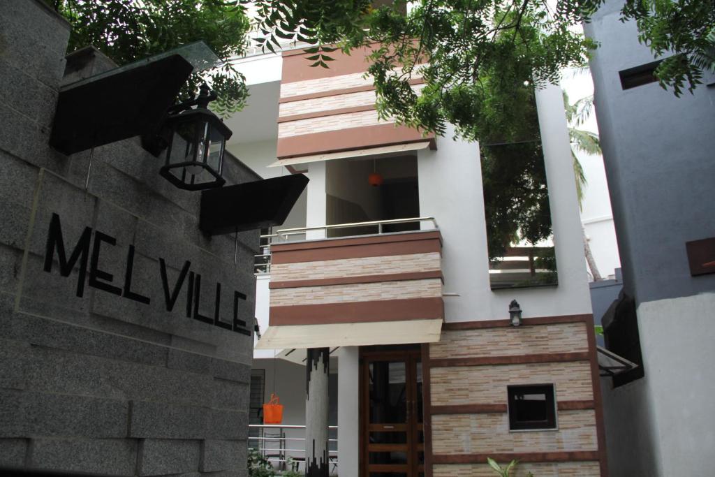 une maison blanche avec une porte en bois et des escaliers dans l'établissement Mel Ville, à Pondichéry