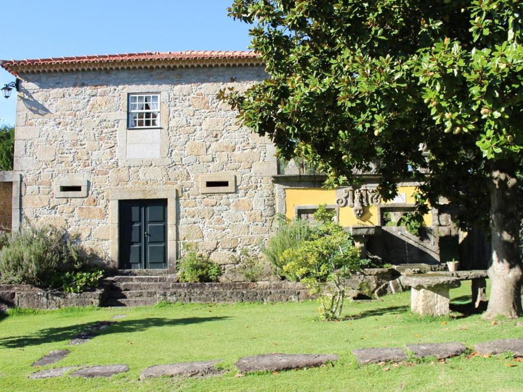 uma casa de pedra com uma árvore em frente em Nice Cottage in Santa Comba with Communal Pool em Ponte de Lima