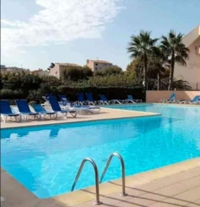 - une grande piscine avec des chaises longues bleues dans un complexe dans l'établissement Cap d'Agde méditerranée studio 4 pers piscine rdc parking gratuit, au Cap d'Agde