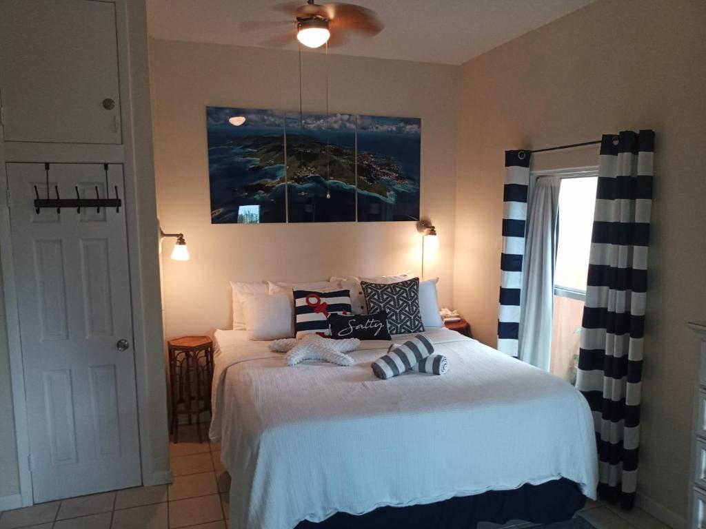 1 dormitorio con 1 cama y una pintura en la pared en Juliette - Studio, Sunset ocean views, pool., en Cruz Bay