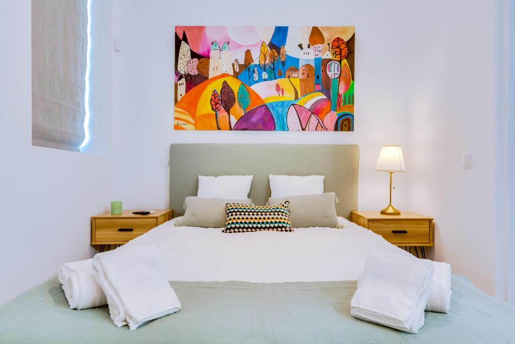 um quarto com uma cama branca e uma pintura na parede em Luminosa Holidays House em Olhão