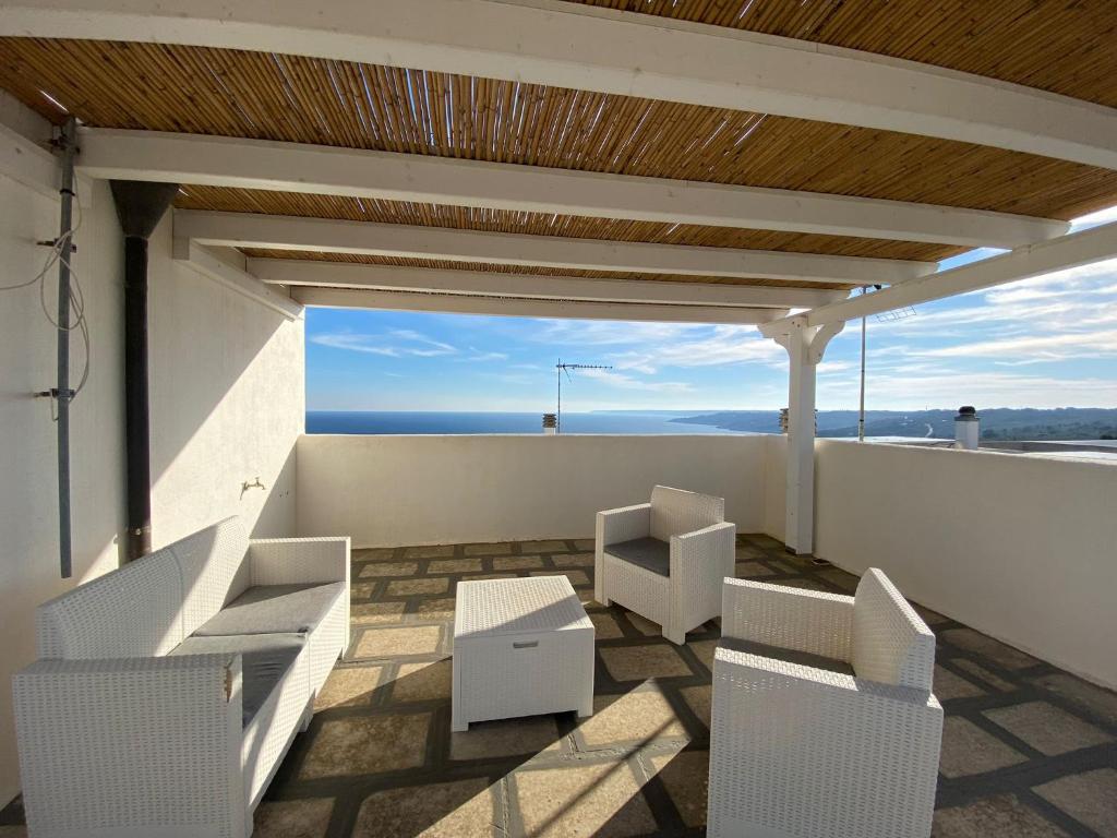 uma varanda com cadeiras brancas e vista para o oceano em Aurora em Santa Cesarea Terme