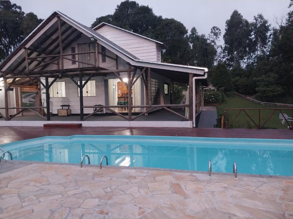 a house with a swimming pool in front of a house at Chacara Recanto Vale do Luar in Piraquara