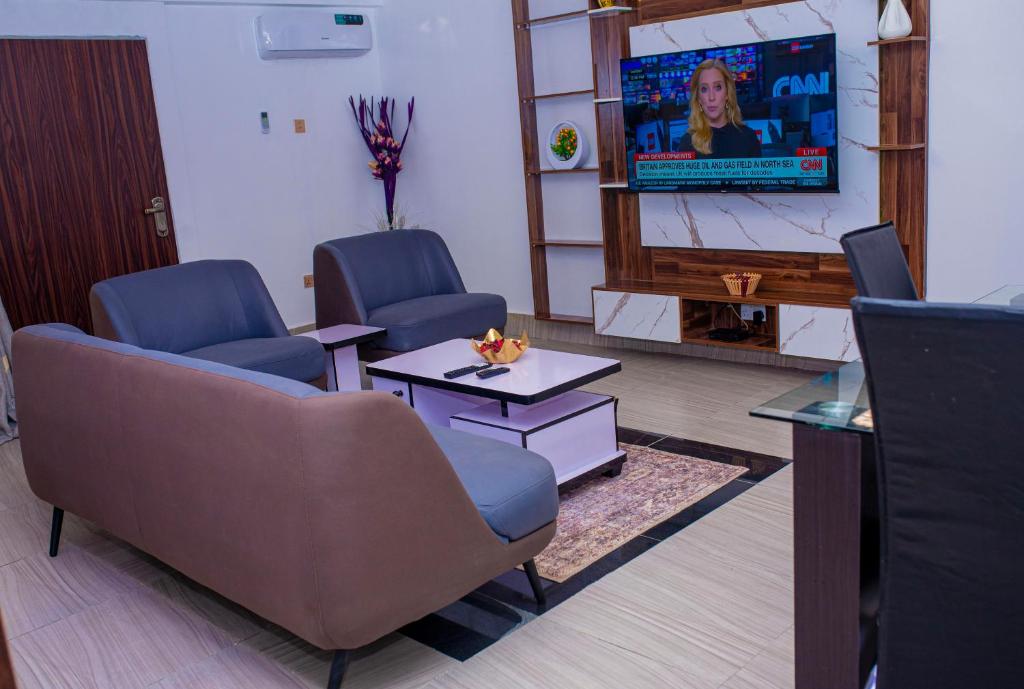 una sala de espera con 2 sillas y TV en Cosystay Apartment, en Abuja