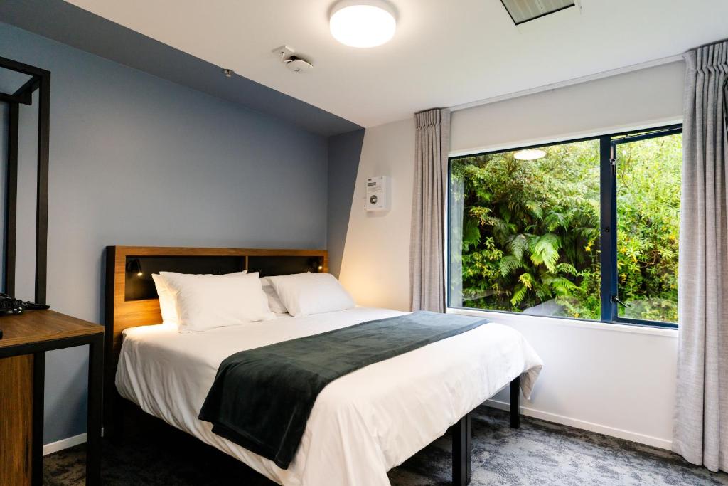 um quarto com uma cama e uma grande janela em Haka House Franz Josef em Franz Josef