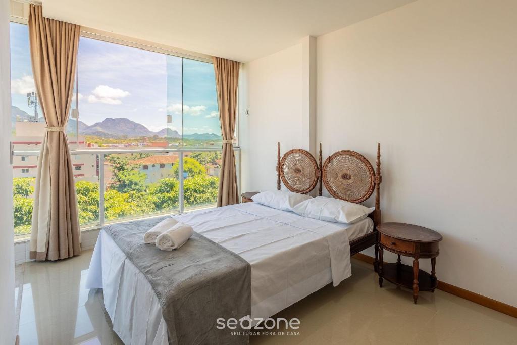 MuquiçabaにあるLindo apto a apenas 400m da Praia do Morro CVE402のベッドと大きな窓のある寝室