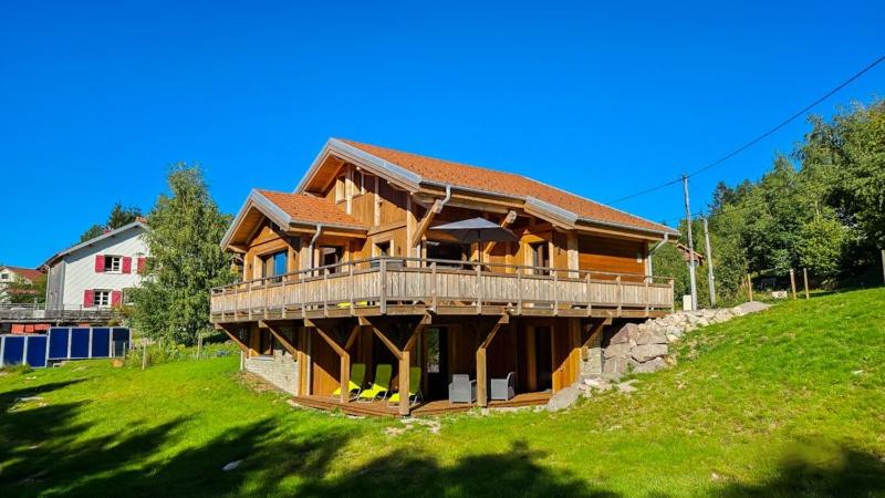 Chalet l'Appel de la Forêt في جوراردُميه: منزل خشبي كبير على تلة عشبية