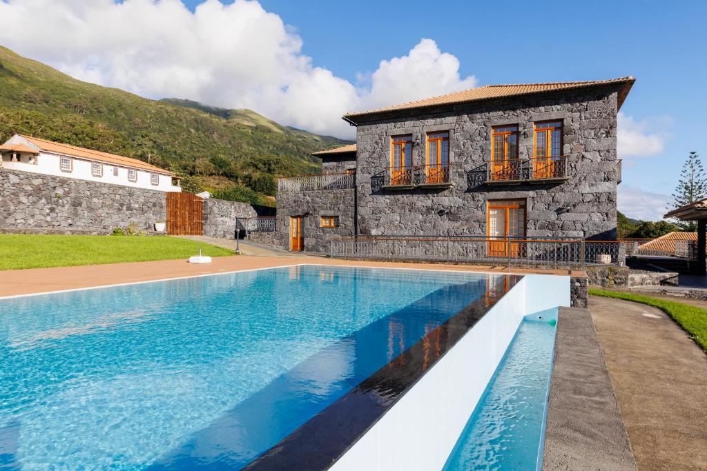 a villa with a swimming pool in front of a house at Quinta da Magnólia AR in Urzelina
