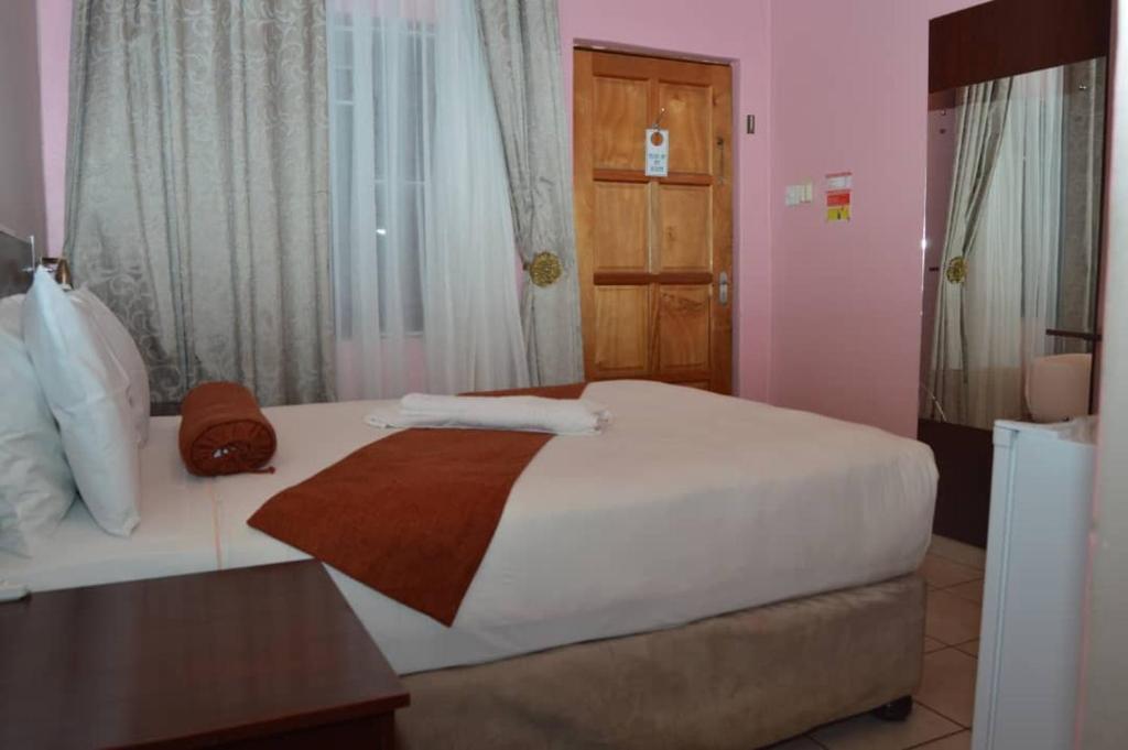 a bedroom with a white bed and a wooden door at MOGONONO SELECTED SERVICE HOTEL in Palatswe
