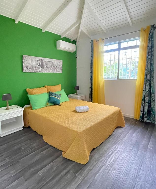 a bedroom with a large bed with a green wall at Résidence Subtropicale in Saint-François