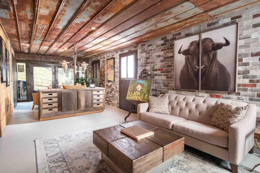 a living room with a couch and a brick wall at Fairytale: Hot Tub & Trout Stream & Petting Zoo? in Sugar Grove