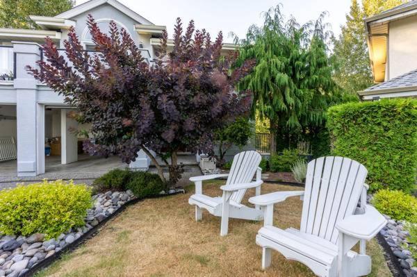 two white chairs sitting in a yard in front of a house at 2 Bedroom Private Guest Suite on a hill in Abbotsford