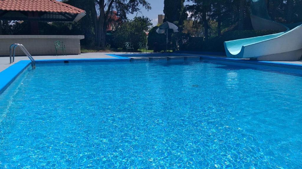 a blue swimming pool with a slide in it at Hotel La Joya Tulancingo in Tulancingo