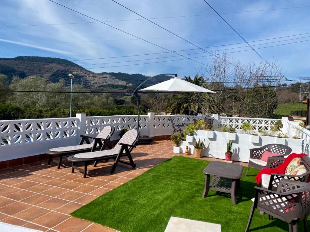 a patio with chairs and grass and a white fence at BILBO Near ático rural con terraza in Basauri