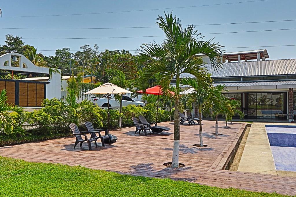 un patio con sedie e una palma accanto alla piscina di Villa Casa Encantadora a Retalhuleu