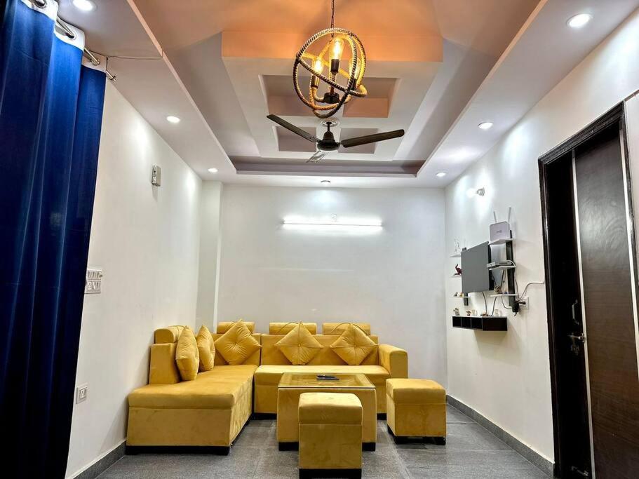a living room with a yellow couch and a ceiling at Cozy 2bhk near Manipal Hospital Dwarka in New Delhi
