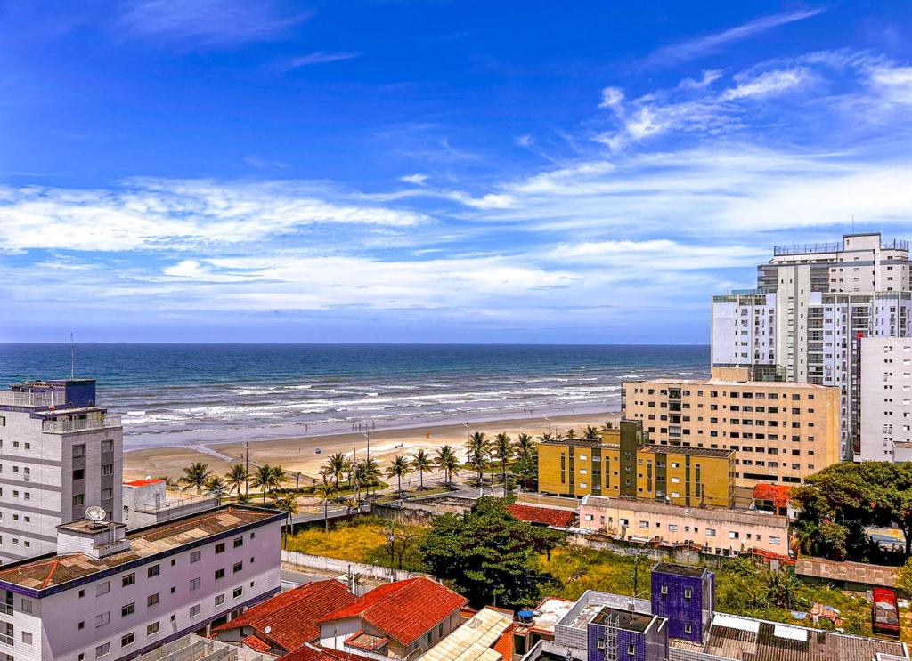 Vila BalneáriaにあるApto com WiFi a 140 metros da Praia do Caicara SPの建物と海のあるビーチの景色