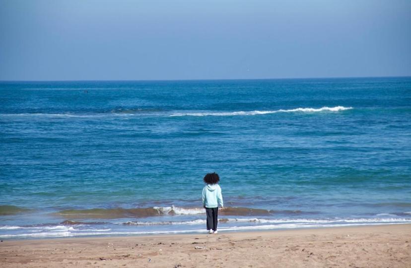 een persoon die op een strand staat en naar de oceaan kijkt bij Villa namaste in Casablanca