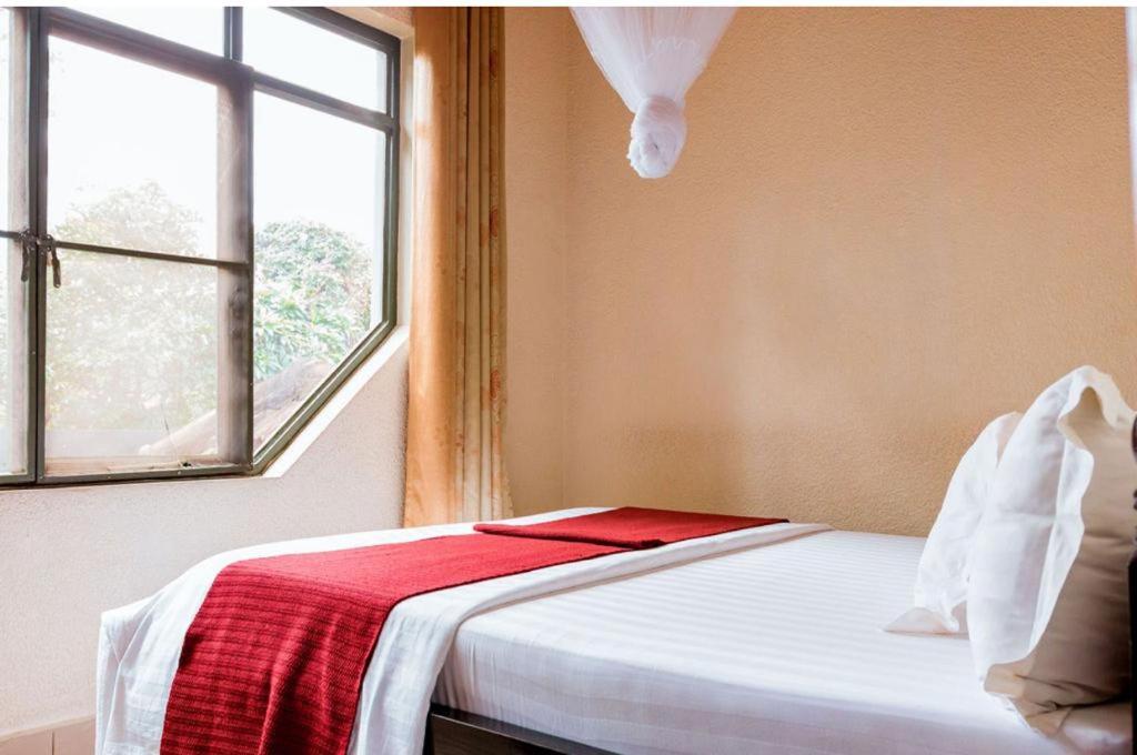 - une chambre avec un lit doté d'une couverture rouge et d'une fenêtre dans l'établissement NYUMBANI CITY CENTER ACCOMODATION, à Kigali